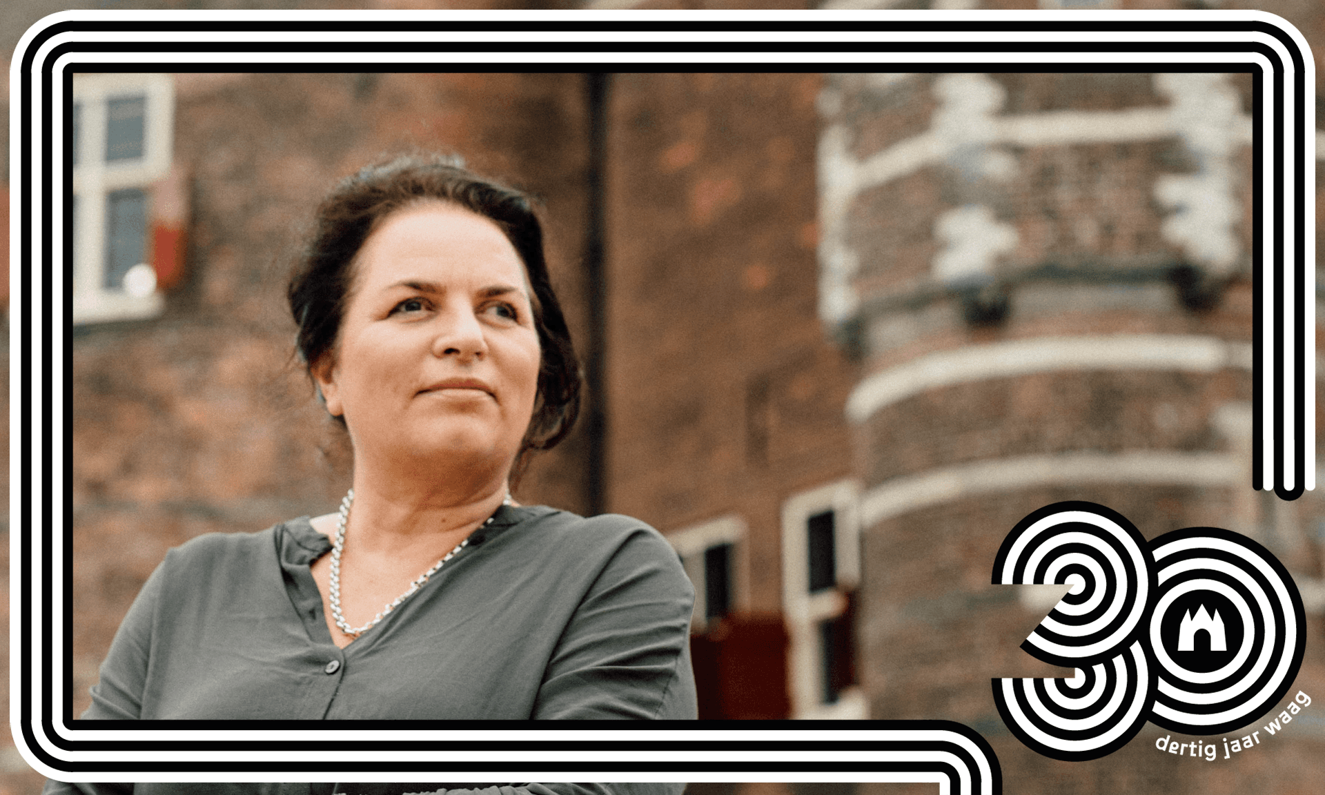 Marleen Stikker staat voor het gebouw de Waag. Ze draagt een grijze blouse en kijkt opzij. 