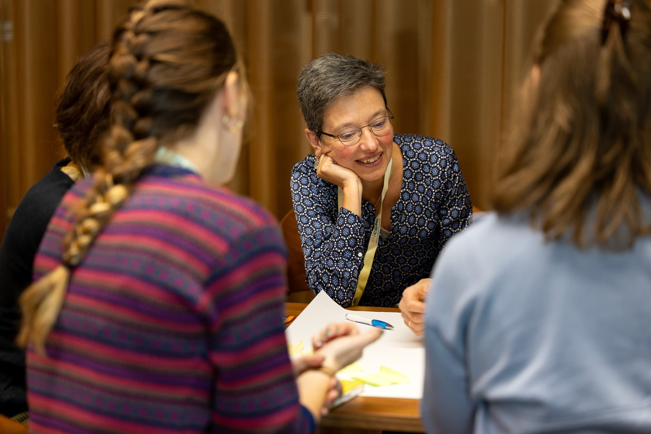 Mensen zitten rond een een tafel en vullen een groot vel in.
