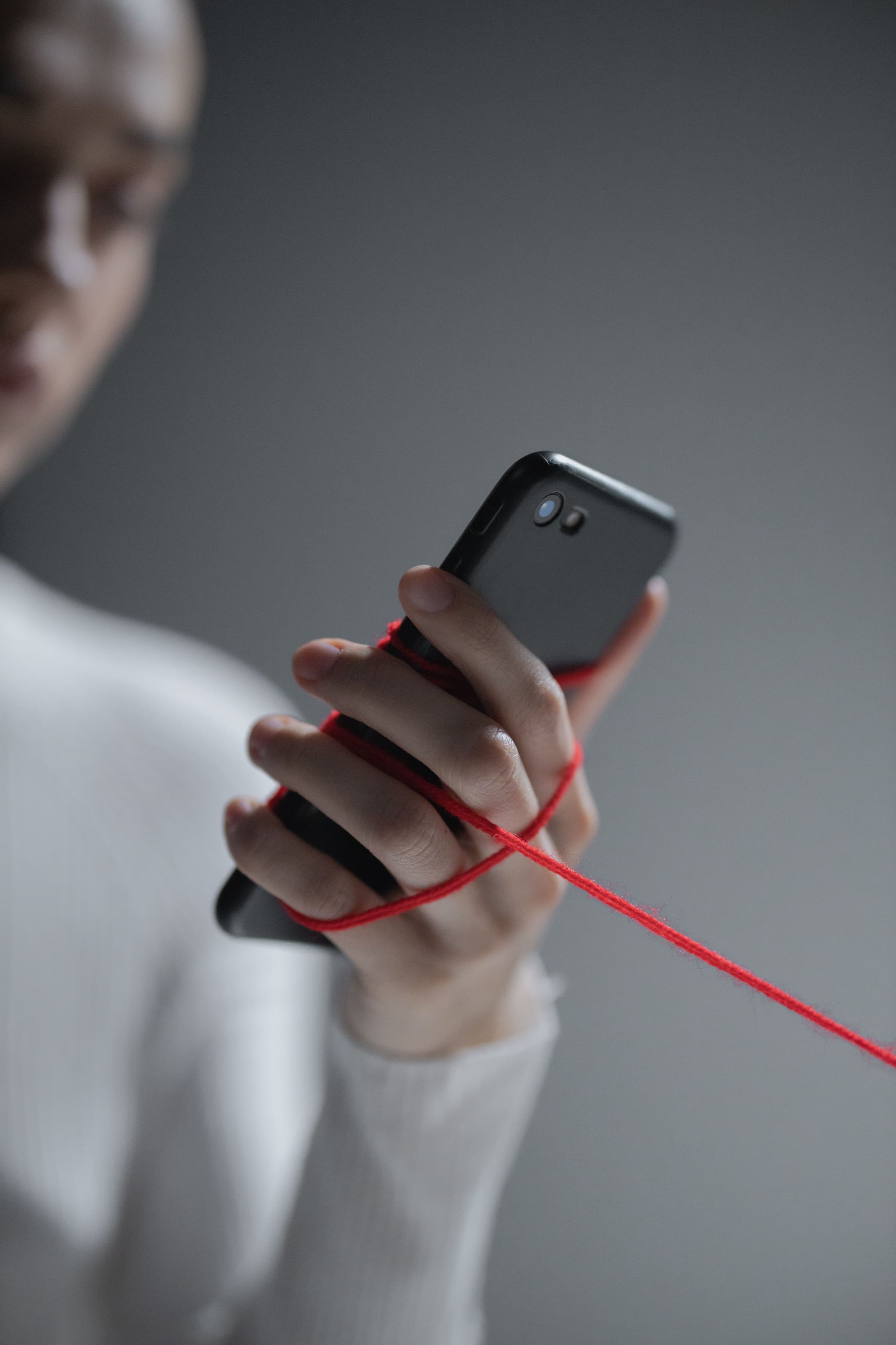 Close-up of a smartphone wrapped in red thread.