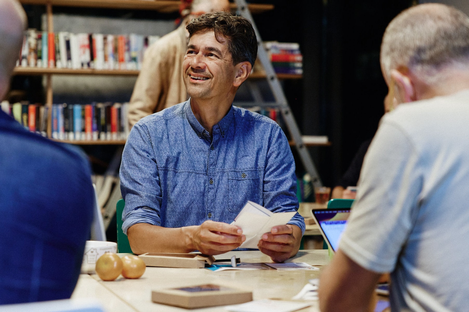 Mensen zijn met elkaar in gesprek aan een tafel in een bibliotheek.