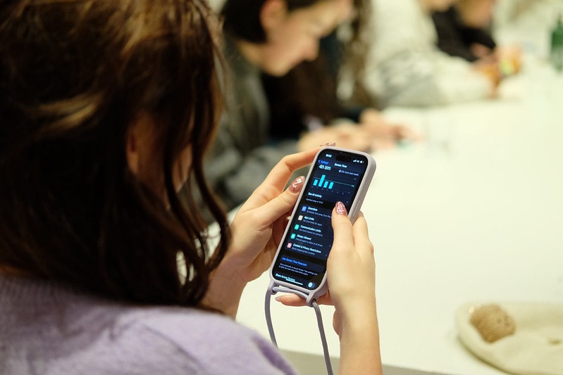 Een vrouw met halflang bruin haar kijkt op haar telefoon naar een grafiek over datagebruik