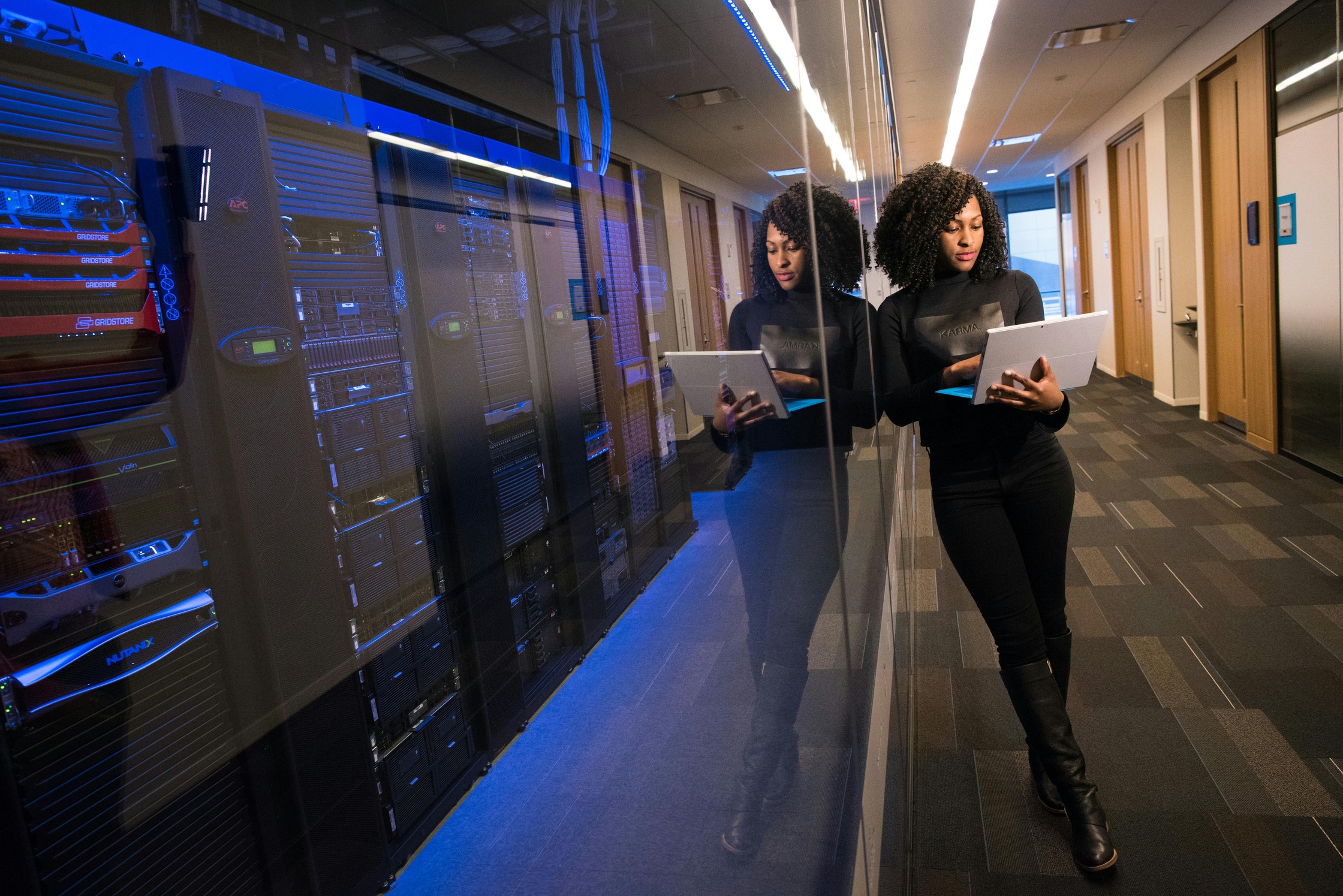 Vrouw staat met laptop naast een grote computer