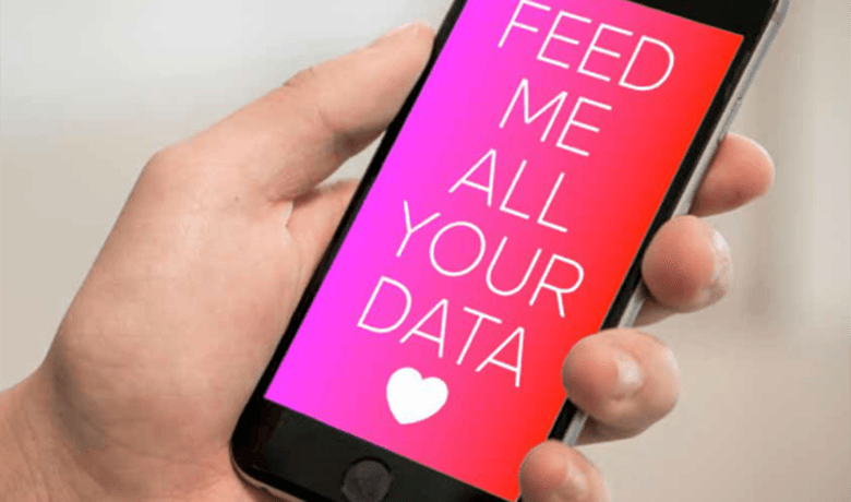 Een witte hand houd een smartphone vast. Op het beeld staat de tekst 'Feed me all your data' met een hartje met een roze-rode achtergrond.