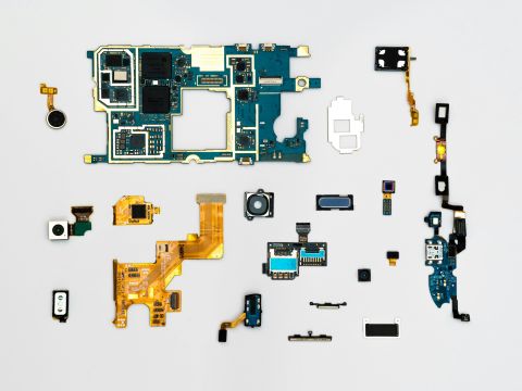 Verschillende stukjes hardware uitgestald tegen een witte achtergrond. Er liggen goudkleurige chips en ook zwarte connectors.