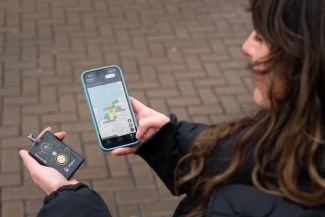 Persoon houdt een meshapparaat en telefoon met kaart van meshgebruikers vast.